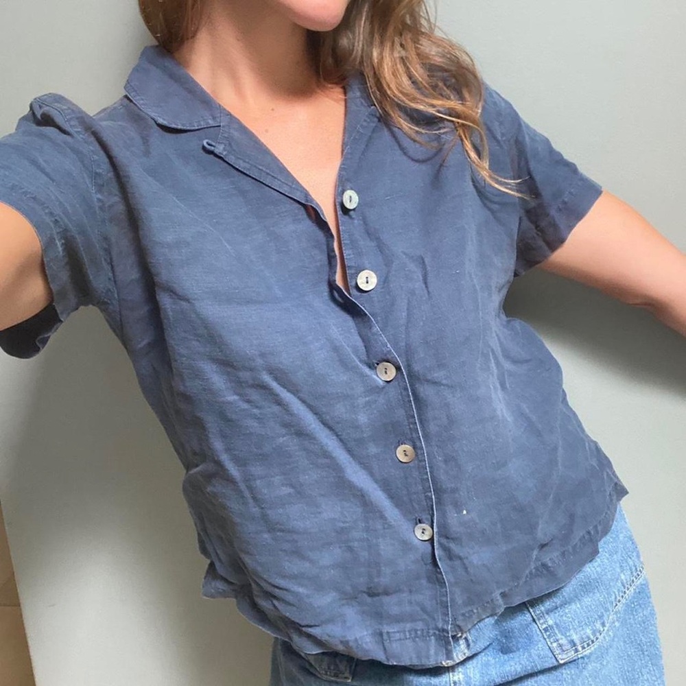 Blue linen shirt with a collared neckline, short sleeves, and button up front.